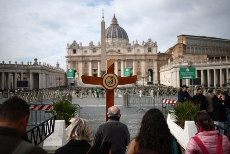 Des pèlerins portent une croix alors que le pape François est admis pour poursuivre son traitement