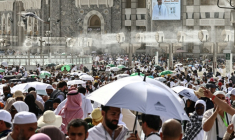 Des fidèles musulmans déambulent dans le complexe de la Grande Mosquée sous les brumisateurs installés dans la ville sainte de La Mecque, le 24 mai 2026 en Arabie saoudite, à la veille du pèlerinage annuel du Hajj ( AFP / Zain JAAFAR )
