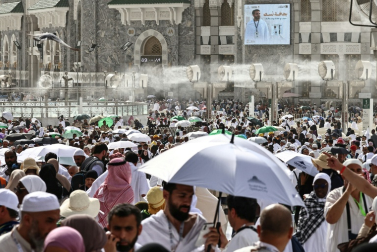 Des fidèles musulmans déambulent dans le complexe de la Grande Mosquée sous les brumisateurs installés dans la ville sainte de La Mecque, le 24 mai 2026  en Arabie saoudite, à la veille du pèlerinage annuel du Hajj ( AFP / Zain JAAFAR )