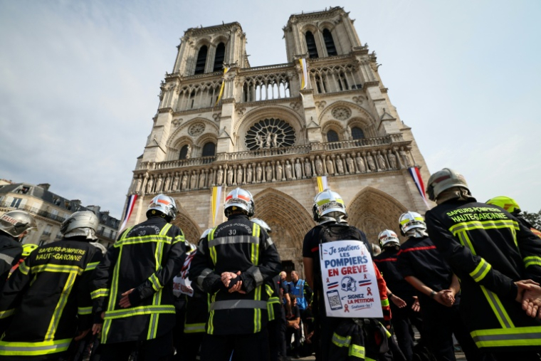 Des sapeurs-pompiers observent une minute de silence devant la cathédrale Notre-Dame de Paris, lors d'une manifestation, le 28 septembre 2026 ( AFP / Xavier GALIANA )