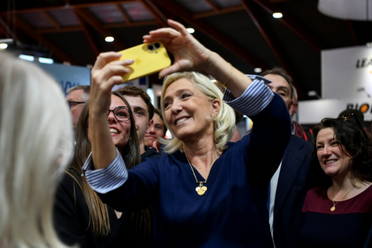 La cheffe de file du Rassemblement nationale, Marine Le Pen, fait un selfie avec des personnes lors du congrès des sapeurs-pompiers au Mans, le 10 octobre 2025 dans la Sarthe ( AFP / JEAN-FRANCOIS MONIER )
