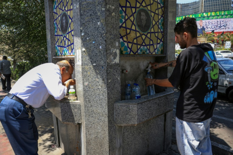 Des passants boivent de l'eau à une fontaine publique dans une rue de Téhéran pendant une vague de chaleur en Iran, le 22 juillet 2025 ( AFP / - )