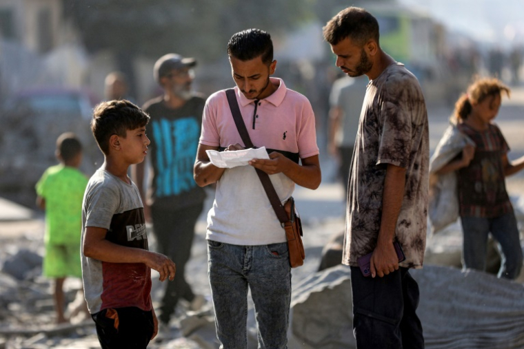 Des habitants de Gaza-ville lisent des tracts largués par l'armée israélienne les appellant à évacuer l'agglomération, la principale du territoire palestinien dévasté par près de deux ans de guerre, le 9 septembre 2025 ( AFP / Omar AL-QATTAA )