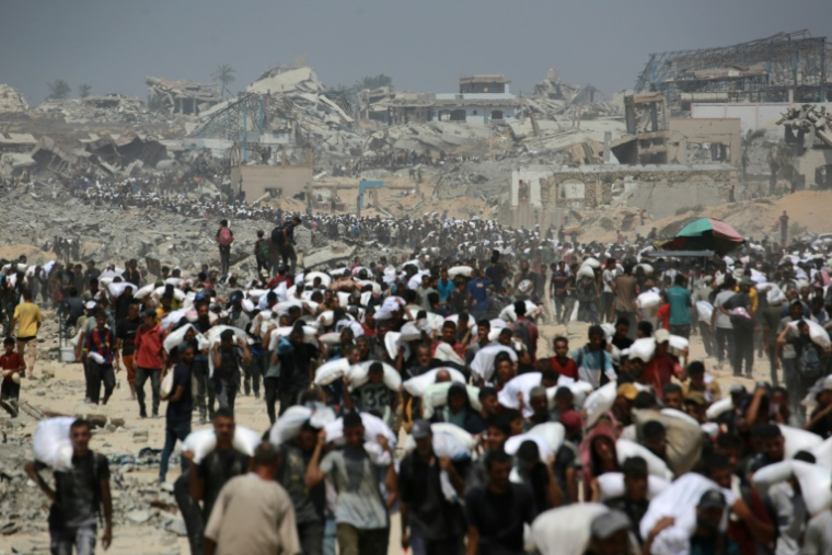 Des Palestiniens transportent des sacs de farine, près de Jabaliya, dans le nord de la bande de Gaza, le 27 juillet 2025 ( AFP / BASHAR TALEB )