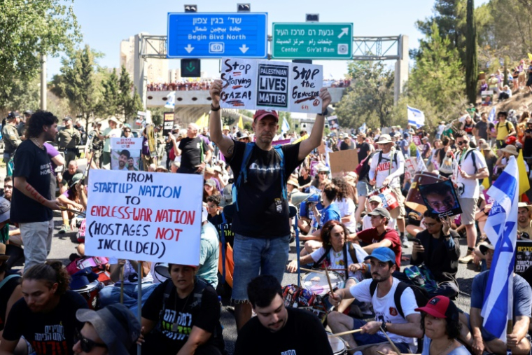 Des familles d'otages retenus dans la bande de Gaza et personnes les soutenant brandissent des panneaux et drapeaux israéliens lors d'une manifestation appelant à les libérer, à Jérusalem, le 17 août 2025 ( AFP / Menahem Kahana )