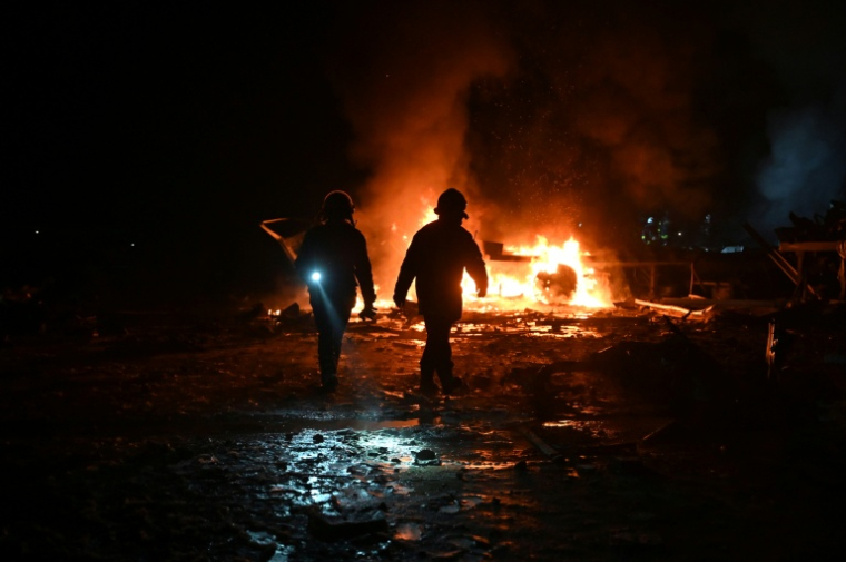 Des pompiers luttent contre un incendie provoqué par un bombardement russe sur un entrepôt de la compagnie des postes Nova Pochta dans un village près de Kharkiv, le 13 janvier 2026 en Ukraine ( AFP / SERGEY BOBOK )