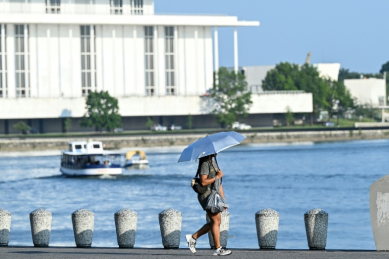 Une passante utilisant un parapluie pour se protéger du soleil et rester au frais, lors de la canicule à Washington, le 1er juillet 2026 ( AFP / Alex WROBLEWSKI )