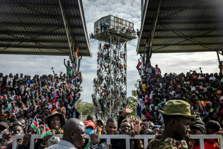 Des partisans de Raila Odinga sont montés sur un château d'eau près du stade où est exposée la dépouille de l'opposant, à Kisumu, dans l'ouest du Kenya, le 18 octobre 2025 ( AFP / Luis TATO )