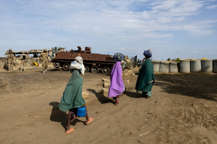 Des piétons passent devant un poste de contrôle pour sortir de Monguno, dans l'État de Borno, au Nigeria, le 4 juillet 2025.  ( AFP / Joris Bolomey )