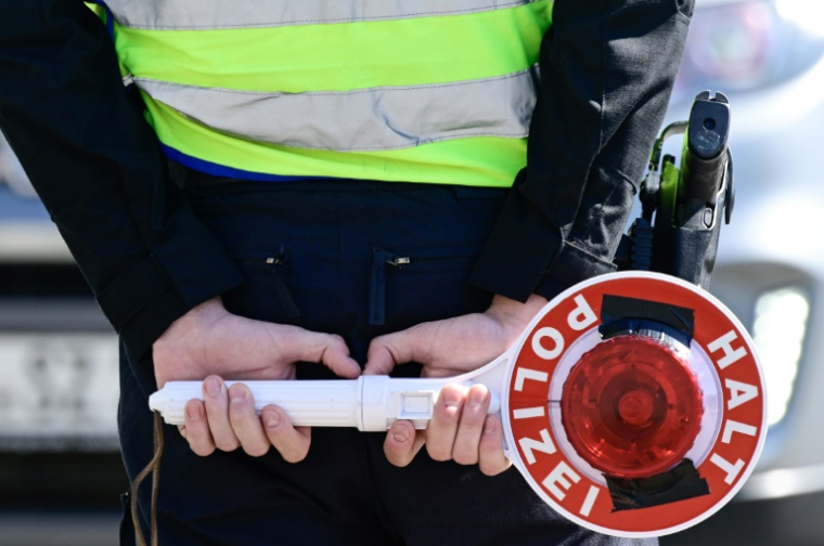 Un policier allemand tient un panneau "Stop police", à la frontière polonaise, à Guben (est de l'Allemagne), le 9 mai 2025 ( AFP / John MACDOUGALL )