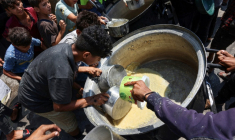 Des enfants palestiniens tentent de prendre ce qui reste dans un récipient de soupe aux lentilles dans un point de distribution de nourriture dans la ville de Gaza, le 25 juillet 2025 ( AFP / Omar AL-QATTAA )