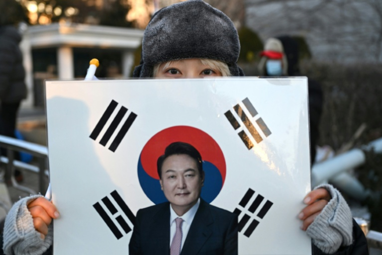 Une supportrice tient un portrait de l'ancien président sud-coréen destitué, Yoon Suk Yeol, devant le tribunal du district central de Séoul où doit se tenir son dernier procès pénal pour insurrection, le 13 janvier 2026 ( AFP / Jung Yeon-je )