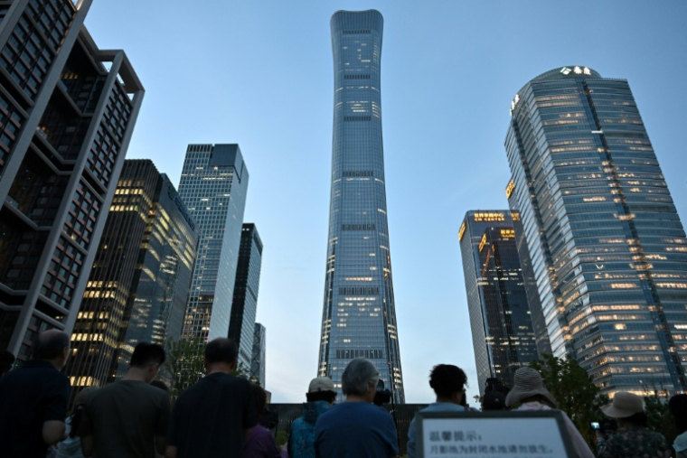 Des personnes rassemblées près de la tour CITIC à Pékin, après que des témoins ont signalé la présence de débris d'avion au pied du plus haut bâtiment de la ville, le 26 juin 2026 en Chine ( AFP / Adek BERRY )
