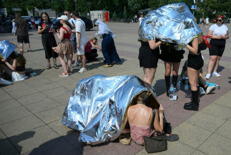 Des spectateurs se protègent de la chaleur avant un concert de Bruo Mars à l'Olympic stadium  de Berlin, le 28 juin 2026 ( AFP / RALF HIRSCHBERGER )
