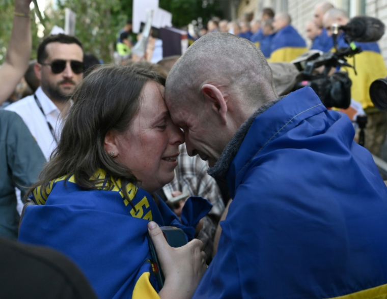 Le prisonnier de guerre ukrainien Oleksandre (d) embrasse sa femme Olena (g), à son arrivée après un échange de prisonniers dans la région de Tcherniguiv, le 23 mai 2025 ( AFP / Genya SAVILOV )