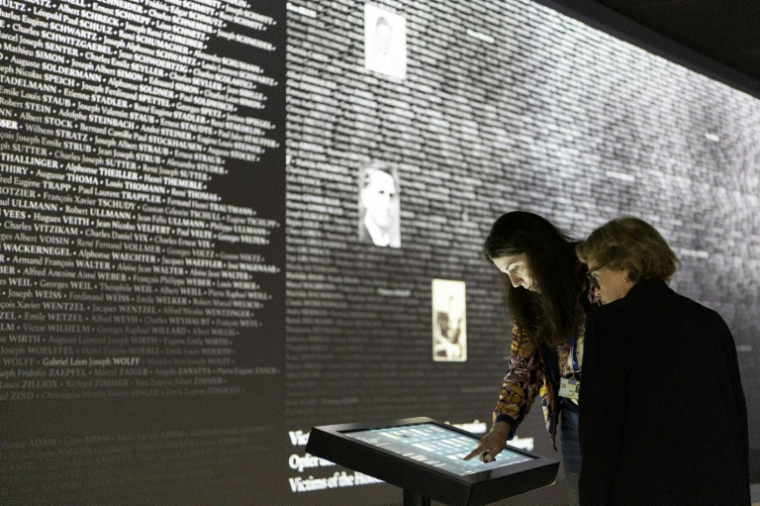 Des visiteuses utilisent une borne interactive pour afficher un nom devant le "Mur des Noms" dédié aux Alsaciens et Mosellans morts durant la Seconde Guerre mondiale à Schirmeck, le 24 septembre 2026 dans le Bas-Rhin ( AFP / ROMEO BOETZLE )