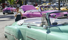 Une touriste prend en photo une voiture américaine dans une rue de La Havane, le 11 février 2026 à Cuba ( AFP / YAMIL LAGE )