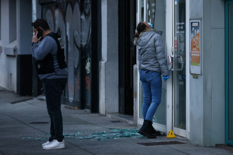 Des policiers examinent la vitrine d'un salon de beauté contre lequel une grenade a été lancée à Grenoble, le 6 février 2026 en Isère ( AFP / Alex MARTIN )