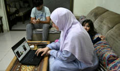 Saniya Jafri, médecin et praticienne en télémédecine, réalise une consultation en ligne, assise à côté de ses enfants à leur domicile de Karachi (Pakistan), le 7 avril 2026 ( AFP / Rizwan TABASSUM )