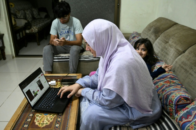 Saniya Jafri, médecin et praticienne en télémédecine, réalise une consultation en ligne, assise à côté de ses enfants à leur domicile de Karachi (Pakistan), le 7 avril 2026 ( AFP / Rizwan TABASSUM )
