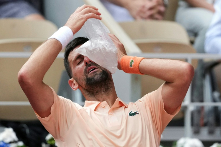 Novak Djokovic tente de se rafraîchir avec une poche de glace, le 29 mai 2026 à Roland-Garros ( AFP / Dimitar DILKOFF )