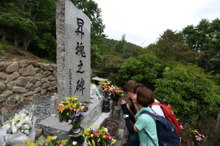 Des proches des victimes de l'accident du vol 123 de Japan Airlines en 1985 se recueillent devant le monument funéraire situé sur le site du crash sur le mont Osutaka au Japon le 12 août 2025. ( JIJI Press / STR )