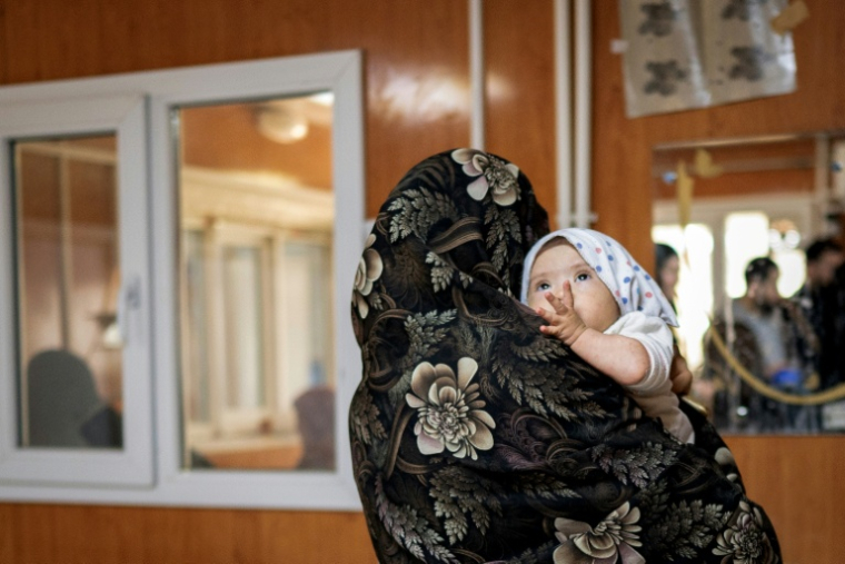 Jamila, une femme afghane, porte sa fille de huit mois après un entretien avec l’AFP au centre de Médecins sans frontières (MSF) d’un hôpital de Hérat le 8 janvier 2026 ( AFP / Wakil KOHSAR )