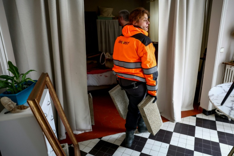 Des membres de la réserve citoyenne apportent des parpaings chez un habitant pour surélever des meubles après les crues, le 20 février 2026 à Saintes, en Charente-Maritime ( AFP / ROMAIN PERROCHEAU )