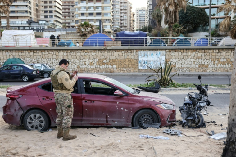 Un soldat inspecte un véhicule endommagé sur le site d'une frappe aérienne israélienne dans la zone côtière de Ramlet al-Bayda à Beyrouth, le 12 mars 2026 au Liban ( AFP / Anwar AMRO )