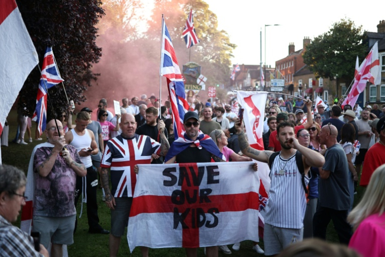 Des manifestants appellent à la fermeture de l'hôtel The Bell, censé héberger des demandeurs d'asile, à Epping, au nord-est de Londres, le 8 août 2025 ( AFP / HENRY NICHOLLS )