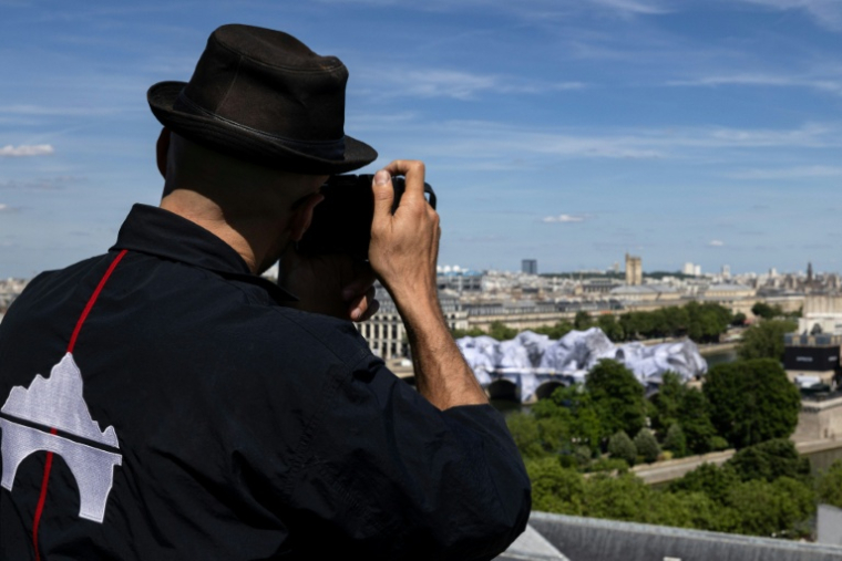 L'artiste français JR photographie sa dernière oeuvre la "Caverne" installée sur le Pont-Neuf à Paris, le 1er juin 2026 ( AFP / Joel Saget )