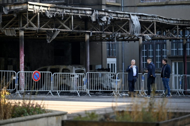 Le maire de Metz, Francois Grosdidier (G) près de véhicules incendiés sous le préau du collège François Rabelais à Metz, le 3 octobre 2026  ( AFP / Jean-Christophe VERHAEGEN )