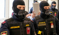 L'ancien général syrien et accusé Khaled al-Halabi (c) cache son visage alors qu'il est escorté par des agents de justice pour son procès au tribunal régional de Vienne, le 1er juin 2026 en Autriche ( AFP / Joe Klamar )