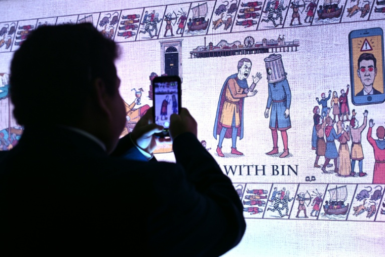 Un militant conservateur regarde la  "Tapisserie de Birmingham" inspirée de la tapisserie de Bayeux et tournant en dérision les adversaires politiques du parti, au premier jour du congrès annuel du Parti conservateur à Birmingham, dans le centre de l'Angleterre, le 4 octobre 2026. ( AFP / Oli SCARFF )