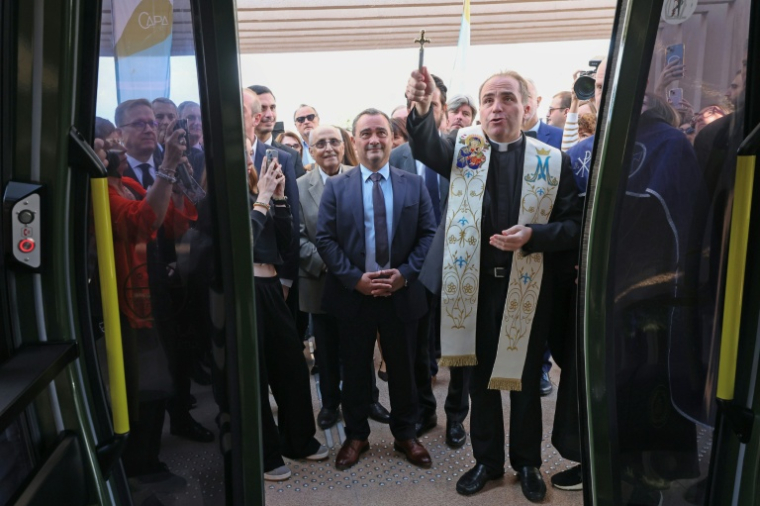 L'abbé Frédéric Constant(R) bénit le téléphérique urbain "Angelo" en présence du maire d'Ajaccio Stéphane Sbraggia (G) lors d'une cérémonie, le 18 octobre 2025 à Ajaccio ( AFP / Pascal POCHARD-CASABIANCA )