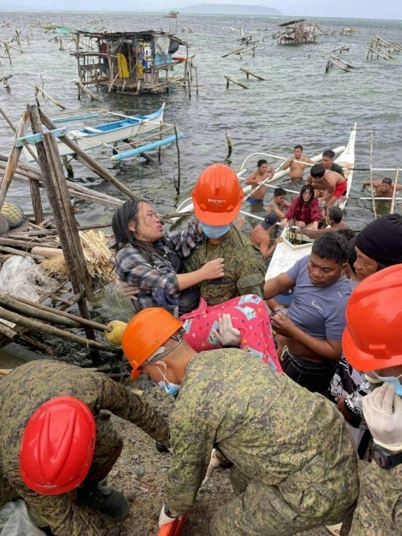 Photo de l'armée philippine montrant des soldats secourant des habitants le 25 septembre 2025 durant le passage de la tempête tropicale Bualoi à Guiuan ( PHILIPPINE ARMY / Handout )