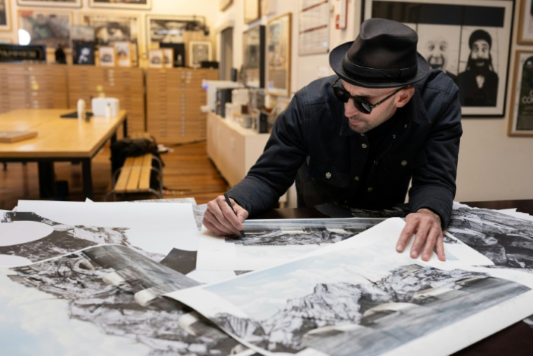 L'artiste JR dans son atelier parisien, le 26 novembre 2025, penché sur son projet de "caverne" sur le Pont Neuf ( AFP / JOEL SAGET )