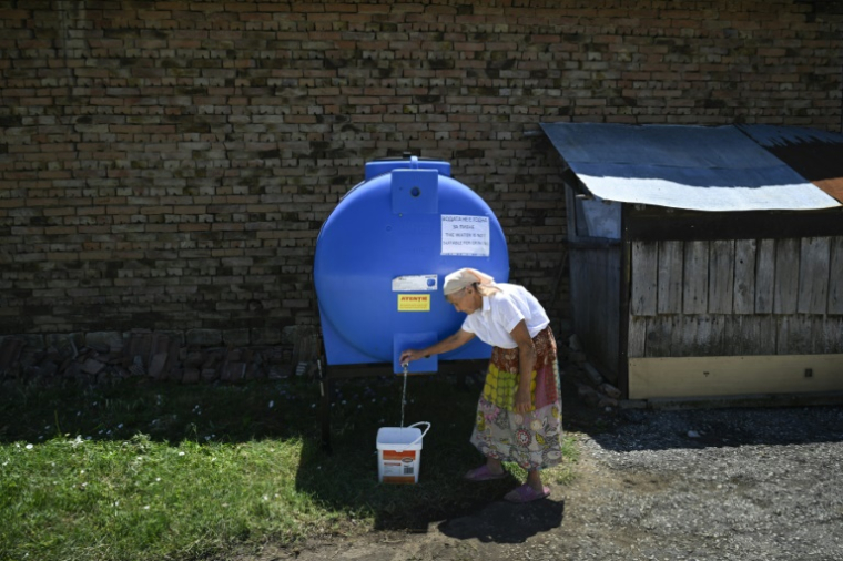Une habitante du village de Gorna Studena remplit un sceau à une citerne d'eau, le 2 juillet 2025 en Bulgarie ( AFP / Nikolay DOYCHINOV )