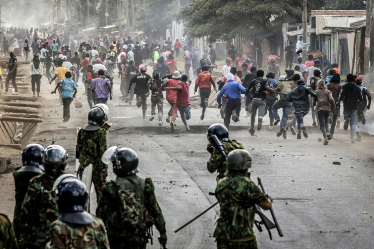 Des manifestants se mettent l'abri lors d'affrontements avec des policiers au cours d'une manifestation contre un centre de quarantaine Ebola construit par les États-Unis sur la base aérienne de Laikipia, le 9 juin 2026 à Nanyuki, au Kenya ( AFP / Luis TATO )