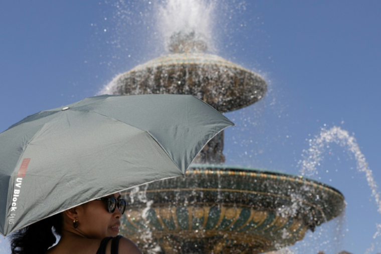 Une femme se protège du soleil avec un parapluie le 27 mai 2026 à Paris ( AFP / JOEL SAGET )
