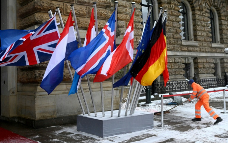Un ouvrier déblaye la neige devant la mairie, l'un des lieux où se tient le Sommet de la mer du Nord, le 26 janvier 2026 à Hambourg, dans le nord de l'Allemagne. ( AFP / Gregor Fischer )