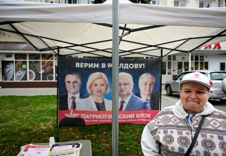 Une activiste du "Bloc patriotique" prorusse se tient devant une tente présentant l'alliance, devant une affiche disant en russe "Nous croyons en la Moldavie!", le 24 septembre 2025 à Ungheni (Moldavie) ( AFP / Daniel MIHAILESCU )