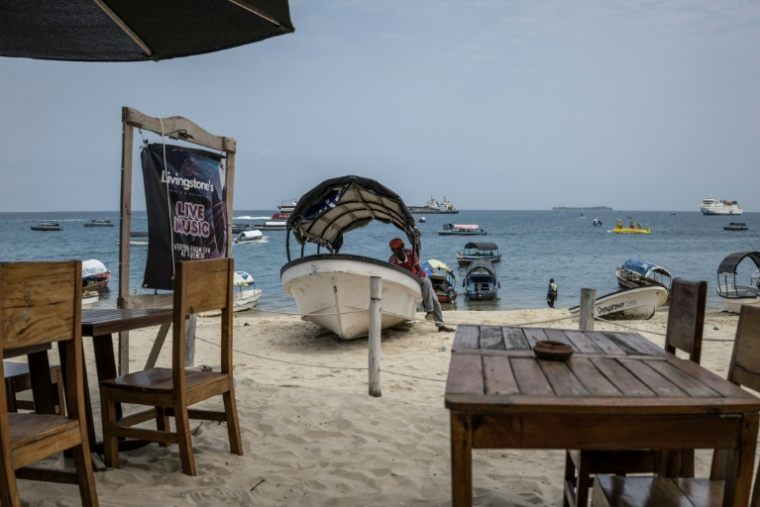 Un commerçant attend les touristes sur son bateau sur la plage de Stone Town, en Tanzanie, le 24 octobre 2025 ( AFP / MARCO LONGARI )