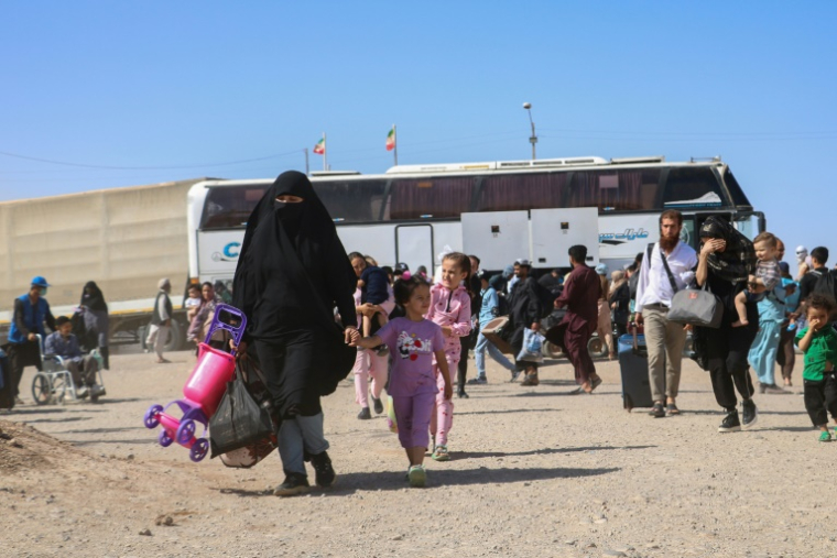 Un bus iranien dépose des réfugiés afghans à la frontière d'Islam Qala, dans la province d'Herat, le 24 juillet 2025 en Afghanistan ( AFP / Mohsen KARIMI )