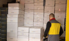 Un livreur se tient à côté de colis Zalando dans un centre de tri suisse