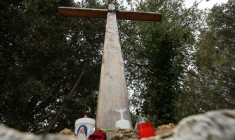 Des bougies déposées au pied d'une croix en bois à l'entrée du village de Quasquara, le 14 octobre 2025 en Corse-du-Sud ( AFP / Pascal POCHARD-CASABIANCA )