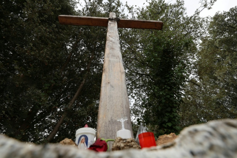 Des bougies déposées au pied d'une croix en bois à l'entrée du village de Quasquara, le 14 octobre 2025 en Corse-du-Sud ( AFP / Pascal POCHARD-CASABIANCA )