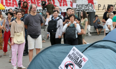 Des touristes prennent des photos des tentes dressées par des manifestants qui protestent contre les expulsions et la crise du logement, le 27 septembre 2026 à Madrid ( AFP / Thomas COEX )