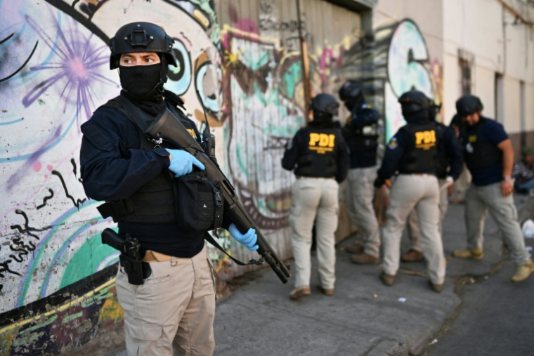 Des policiers pénètrent dans une habitation lors d'une opération antidrogue   à Santiago, le 11 décembre 2025  ( AFP / Rodrigo ARANGUA )