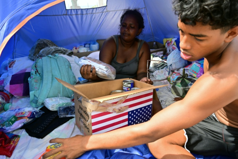 Des déplacés à la suite des séismes du 24 juin examinent le contenu d'un carton d'aide humanitaire américaine dans un centre d'accueil à Catia La Mar, dans l'Etat de La Guaira, au Venezuela, le 8 juillet 2026 ( AFP / MARTIN BERNETTI )